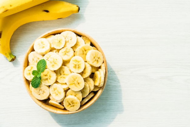 Fette di banana gialla cruda in ciotola di legno