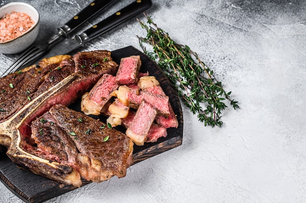 Fette di carne di manzo Tbone alla griglia bistecca su un tagliere di legno.