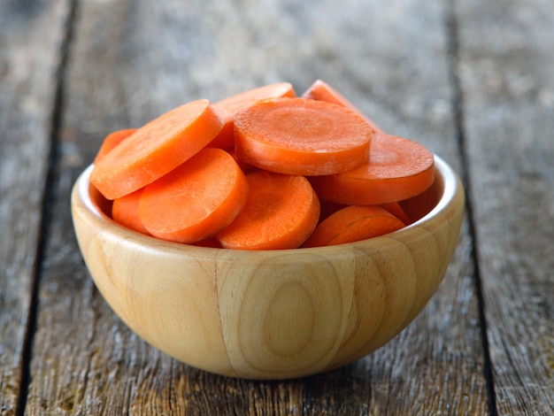 Fette di carota in ciotola di legno