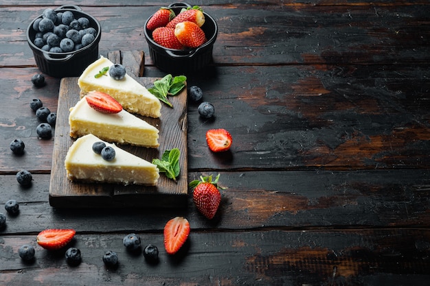 Fette Di Classica New York Cheesecake, Sul Vecchio Tavolo In Legno Scuro Sfondo Con Copia Spazio Per Il Testo