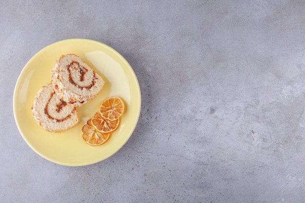 Fette di crema dolce rotolano su un piatto con limone essiccato.