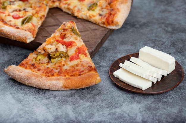 Fette di deliziosa pizza calda con formaggio a fette posto su un tavolo di pietra.
