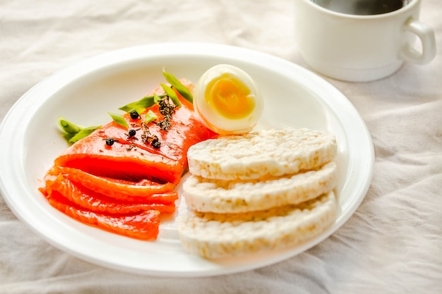 Fette di filetto di pesce crudo salato con uova e gallette di riso. Selezione di buone fonti di grasso - concetto di alimentazione sana. Concetto di dieta chetogenica. Messa a fuoco selettiva