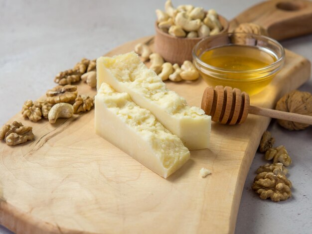 Fette di formaggio a pasta dura su una tavola di legno con noci e miele la migliore combinazione