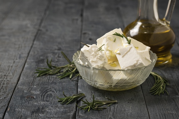 Fette di formaggio feta con olio d'oliva ed erbe aromatiche su un tavolo di legno. Formaggio naturale prodotto con latte di pecora.