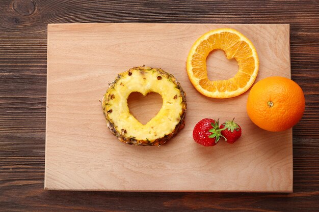 Fette di frutta con taglio a forma di cuore e bacche sul tavolo da vicino