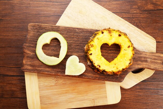 Fette di frutta con taglio a forma di cuore su fondo di legno