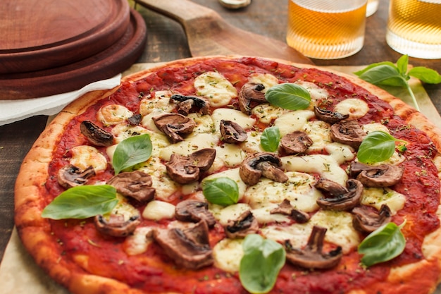 Fette di funghi e foglie di basilico su pizza con salsa di pomodoro