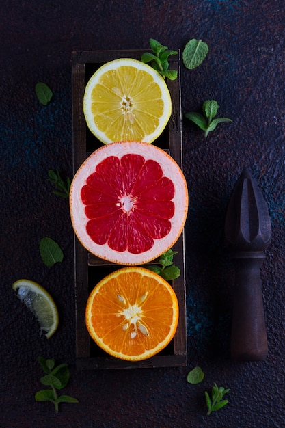 Fette di limone arancione e pompelmo con citrus reamer su sfondo scuro