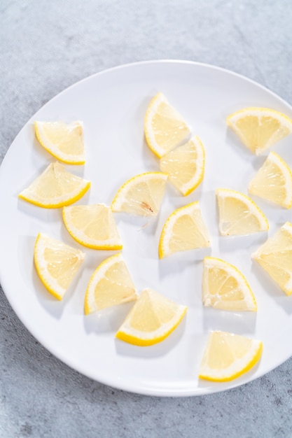 Fette di limone biologico a spicchi su un piatto bianco.