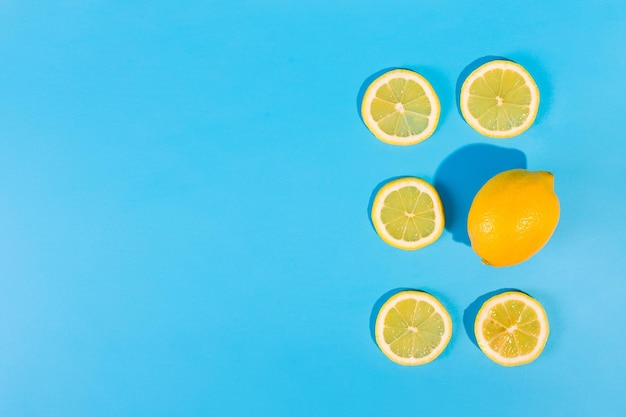 Fette di limone e un limone intero giacciono su uno sfondo blu isolato con copyspace Dieta vitamina c