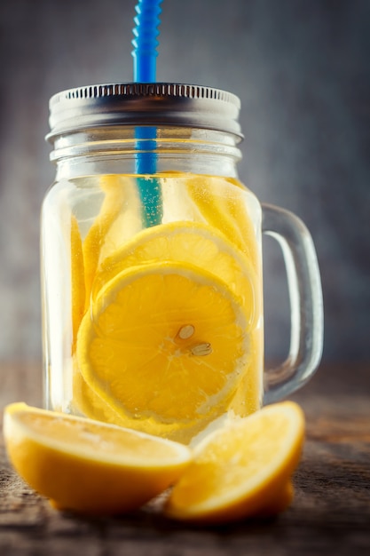 Fette di limone in un barattolo con acqua e un tubo blu