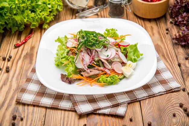 Fette di manzo speziate Insalata di carne con carote, pomodori, cetrioli, prezzemolo, ravanello e foglie Spinaci, rucola, bietola rossa sul vecchio tavolo di legno