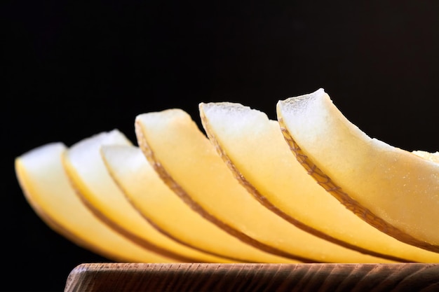 Fette di melone su una tavola di legno su uno sfondo scuro