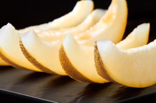 Fette di melone su una tavola di legno su uno sfondo scuro