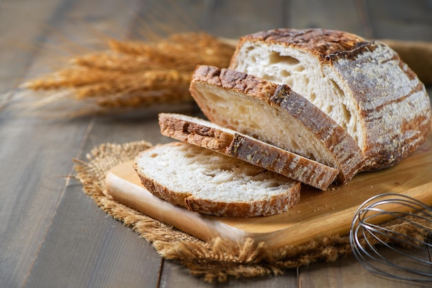 Fette di pane a lievitazione naturale su tavola di legno su fondo di legno panetteria fatta in casa