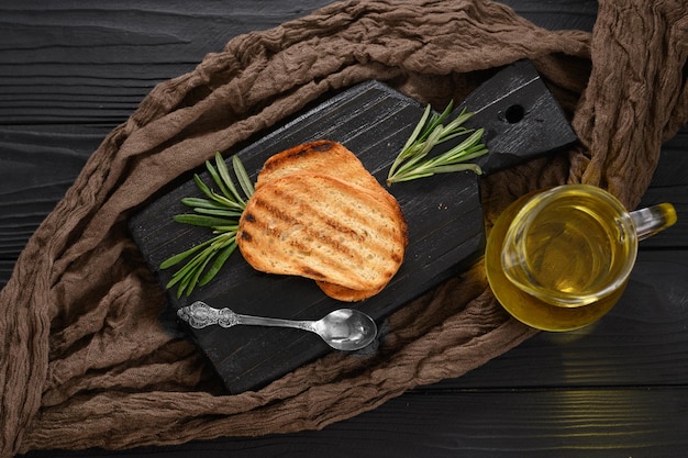 Fette di pane abbrustolito con olio extravergine di oliva e rosmarino su fondo nero