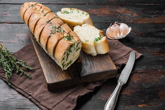 Fette di pane alla griglia con aglio ed erbe aromatiche, su un vecchio tavolo in legno scuro dello sfondo