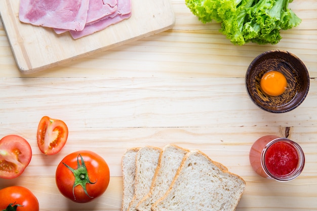 fette di pane con marmellata e prosciutto, tamoto, lattuga, uovo sul tavolo con cucina sul tavolo con cucina