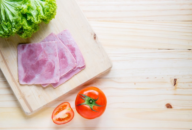 fette di pane e prosciutto, tamoto, lattuga sul tavolo con cucina