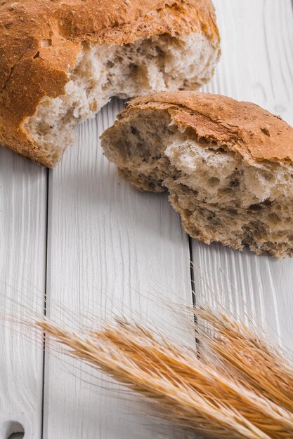 Fette di pane e spighe di grano su vecchie tavole di legno bianche