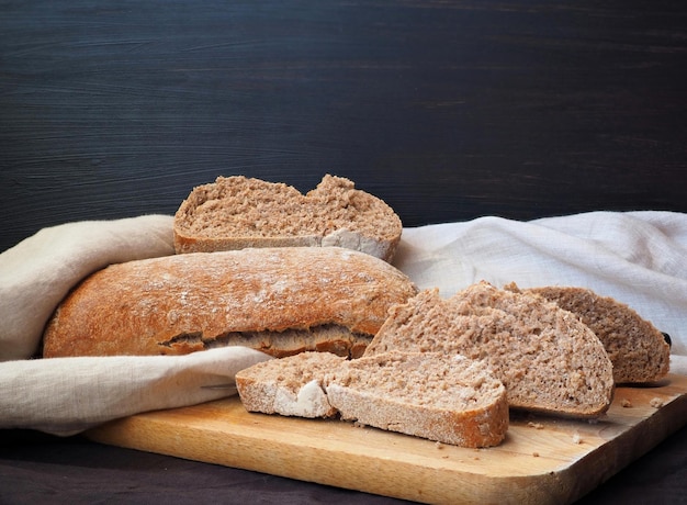 Fette di pane fresco multicereali di pane grigio e nero tagliere in legno panno di lino