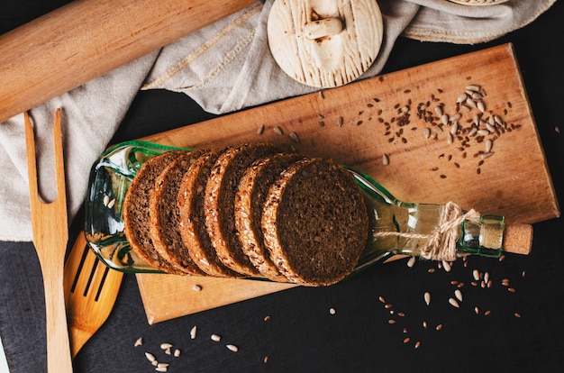 Fette di pane integrale di segale con semi di girasole, lino o semi di lino e sesamo su un piatto fatto in bottiglia