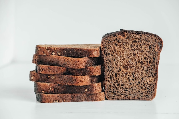 Fette di pane integrale fresco con uvetta su fondo di legno bianco. Copia, spazio vuoto per il testo