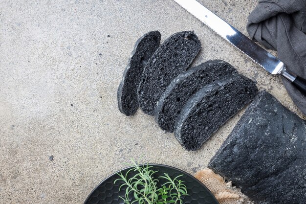 Fette di pane nero colorato con nero di seppia su grigio