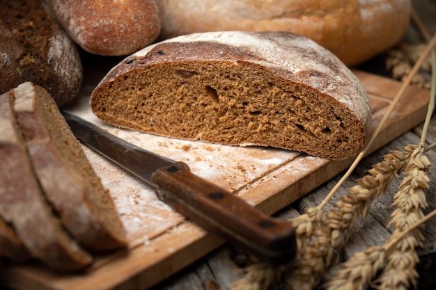 Fette di pane su un tagliere con un coltello e spighette di grano