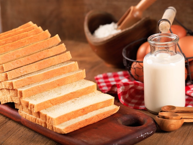 Fette di pane tostato pane bianco (Shokupan o Roti Tawar) per colazione su fondo di legno, servito con uova e latte. Immagine del concetto di panetteria