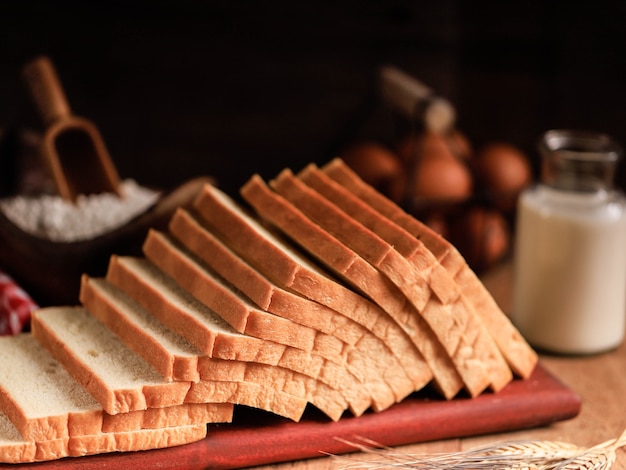 Fette di pane tostato pane bianco (Shokupan o Roti Tawar) per colazione su fondo di legno, servito con uova e latte. Immagine del concetto di panetteria