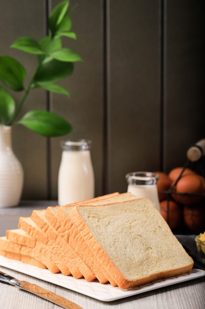 Fette di pane tostato pane bianco (Shokupan o Roti Tawar) per colazione su fondo di legno, servito con uova e latte. Immagine del concetto di panetteria