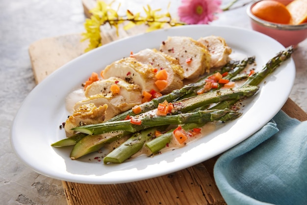 Fette di petto di pollo con asparagi sul piatto