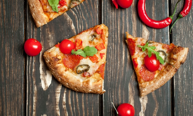 fette di pizza peperoni con ingredienti su fondo di legno