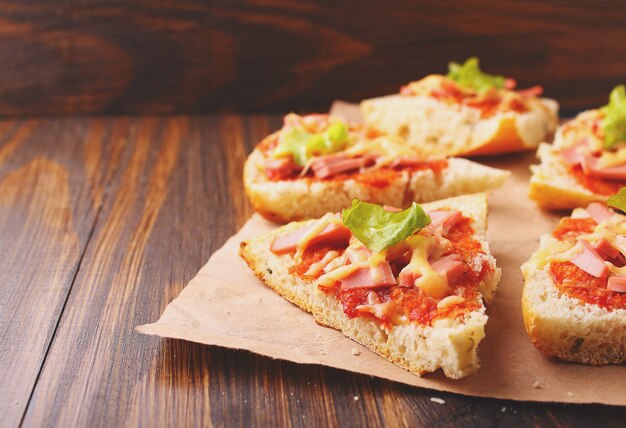 Fette di pizza su pergamena su fondo di legno