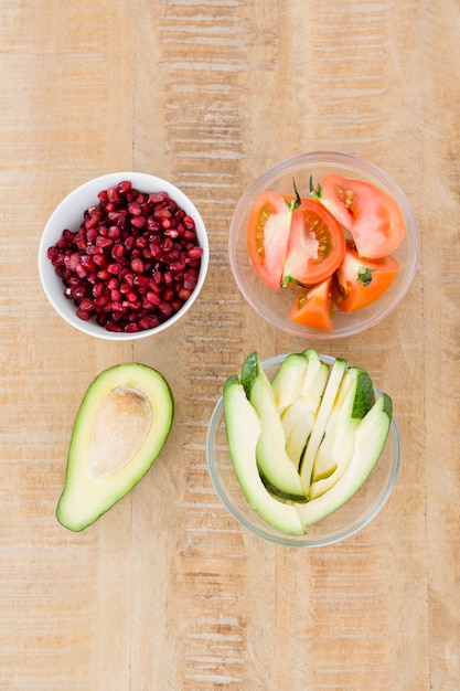 Fette di pomodoro e avocado con semi di melograno in ciotole sul tavolo