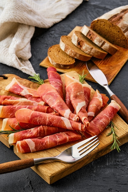 Fette di prosciutto arrotolate sul tagliere di legno