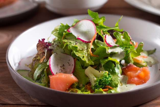 Fette di salmone con insalata di verdure fresche su un piatto.