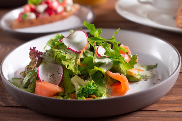 Fette di salmone con insalata di verdure fresche su un piatto.