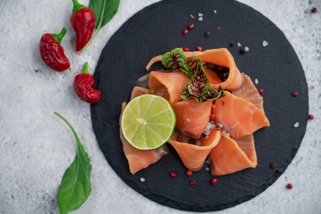 Fette di salmone fresco con peperoni verdi e lime su fondo di cemento