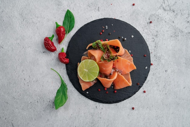 Fette di salmone fresco con peperoni verdi e lime su fondo di cemento