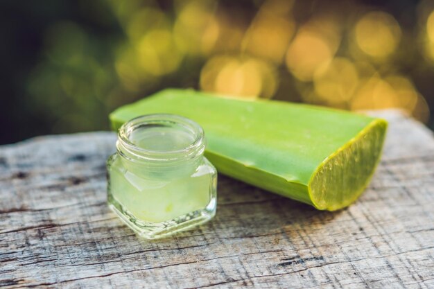 Fette di una foglia di aloe vera e una bottiglia con gel trasparente per scopi medicinali, trattamento della pelle e cosmetici, primo piano