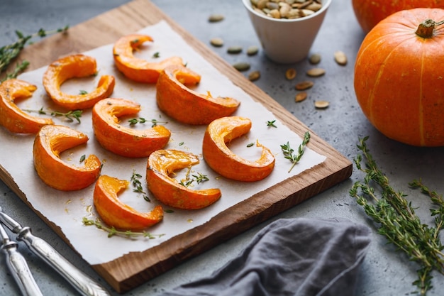 Fette di zucca al forno con timo su una tavola di legno su un tavolo grigio Ricetta vegetariana di cibo stagionale