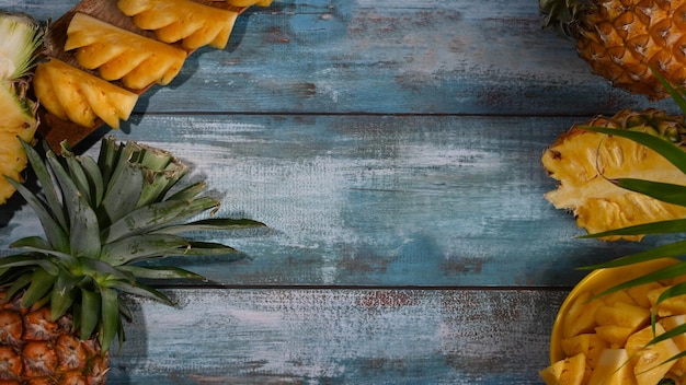 Fette e metà di ananas su sfondo di legno Frutta o concetto di assistenza sanitaria