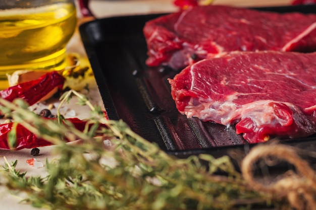 Fette fresche della carne cruda sulla vista superiore della padella. Bistecche di manzo pronte per la cottura con olio d&#39;oliva