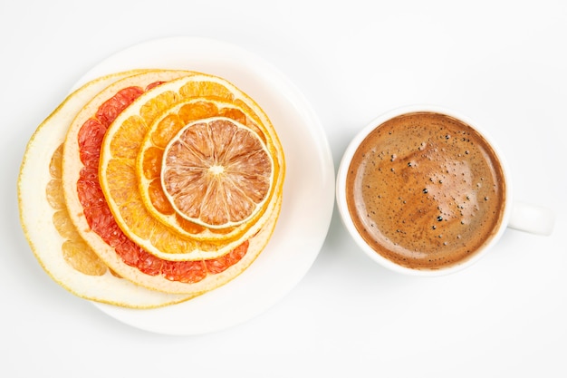 Fette secche di vari agrumi e caffè nero in una tazza bianca