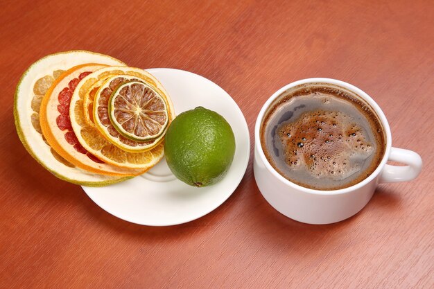 Fette secche di vari agrumi e caffè nero in una tazza bianca