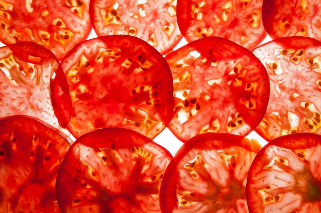 Fette sottili di pomodoro maturo rosso su sfondo chiaro con una luce