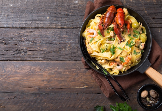 Fettuccine ai frutti di mare con gamberi, polpo e gamberi, su padella di pietra. Piatto gourmet